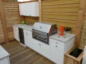 Outdoor kitchen cabinets on a rooftop deck with a grill